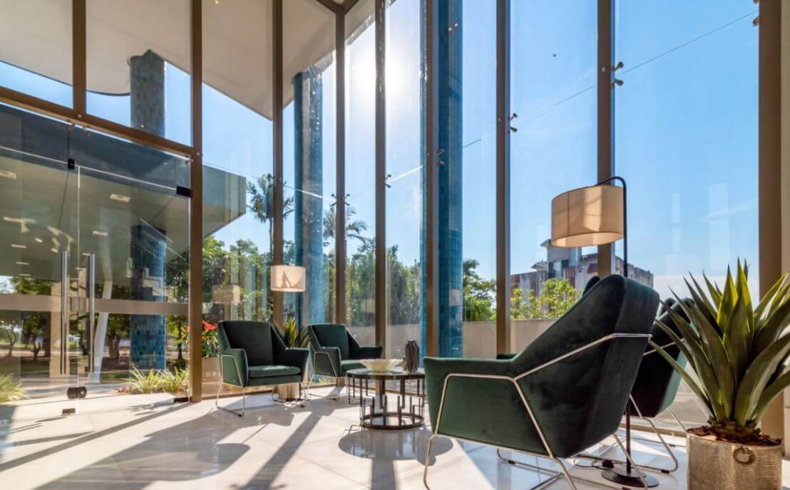 hall apartamento com poltronas verdes, vidraça ampla da Construtora Fontana