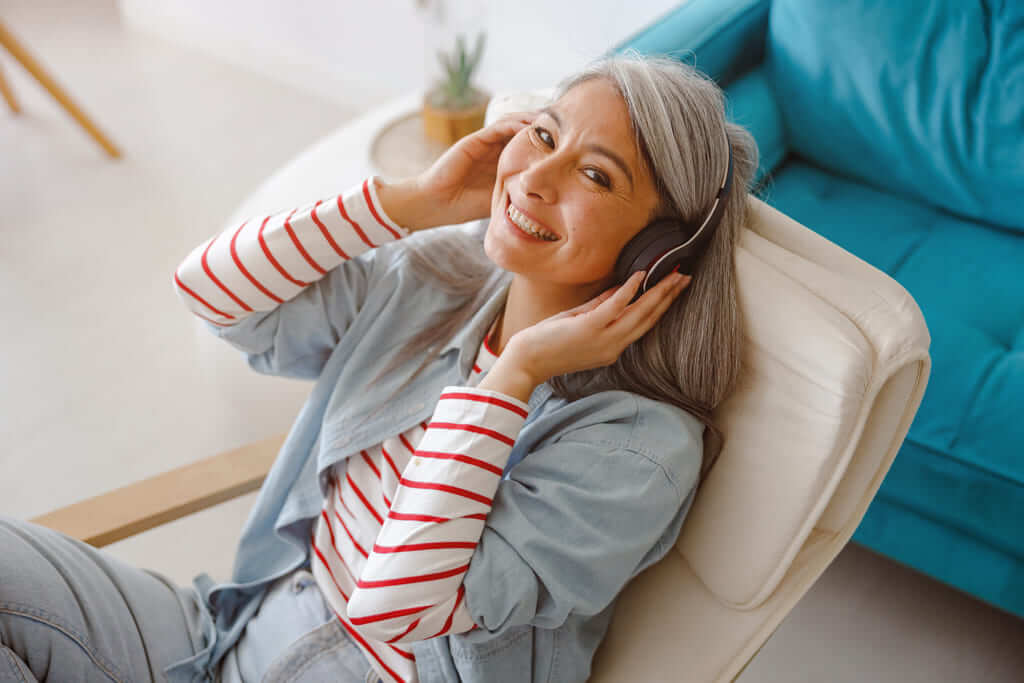 Mulher sorridente escutando música em um apartamento com conforto acústico